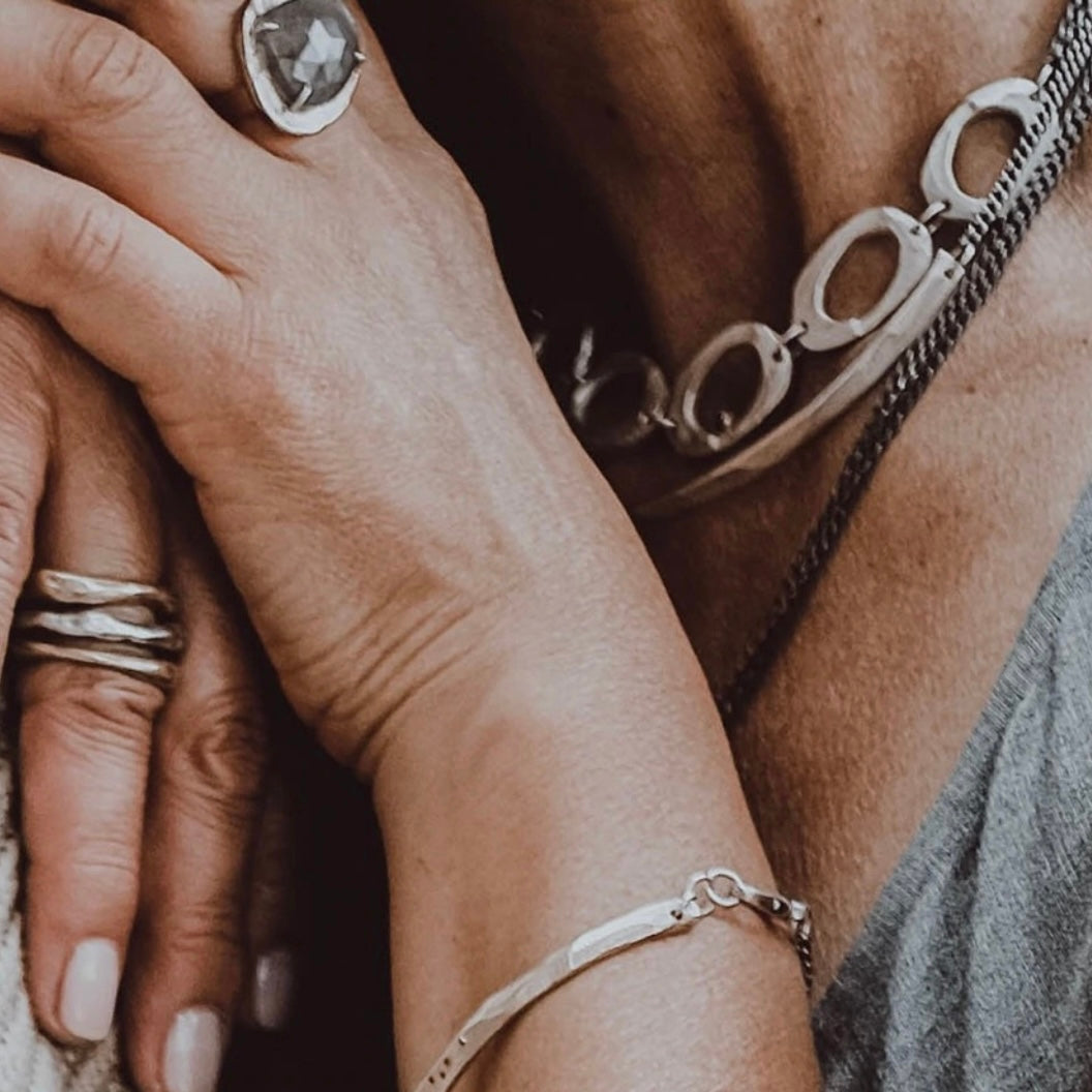 Close-up of hands with jewelry including rings and a bracelet.