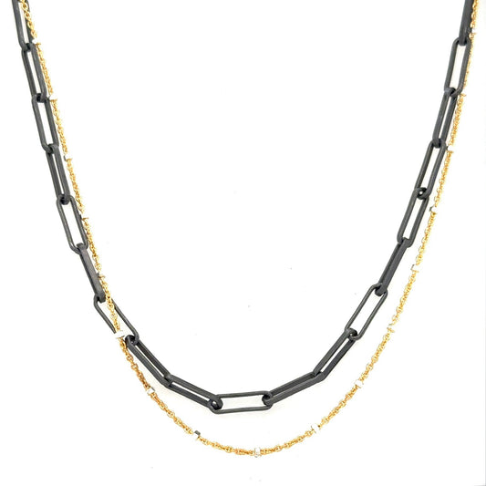 A blend of two worlds in one exquisite piece. This necklace features two chains: one in sophisticated black oxidized sterling silver and the other in luxurious 14K gold-filled metal. The contrasting tones create a subtle yet striking visual interest, perfect for those who appreciate nuanced style.