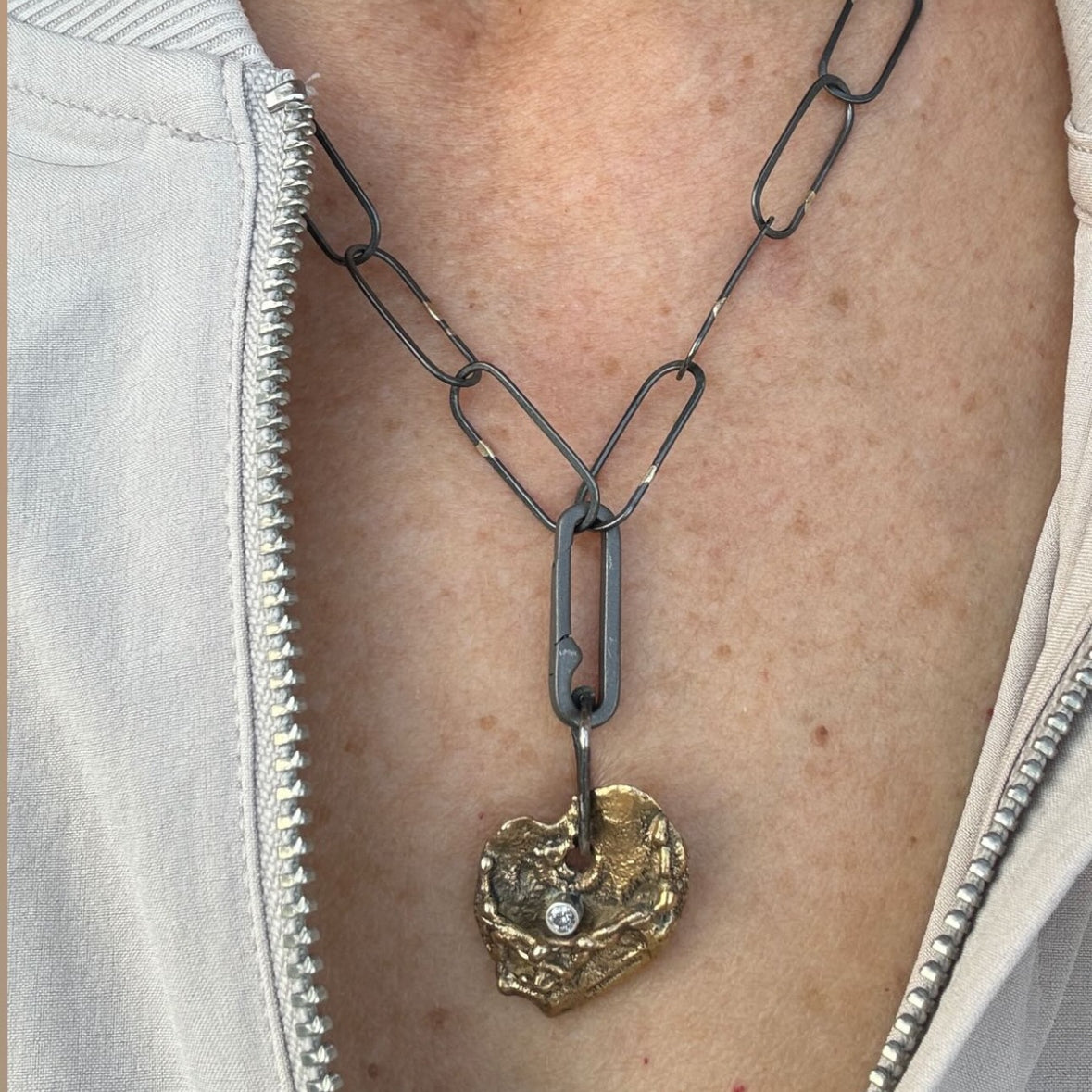 The Love Talisman Necklace on a person wearing a white jacket.
