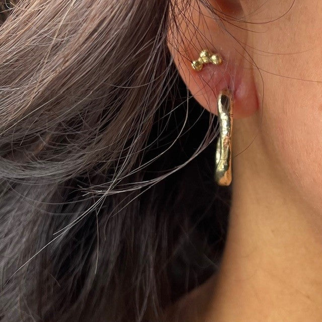 Close up of the Satori 18kt Gold Hoop Earrings and 18kt Gold Hoshi Stud Earrings on a person.