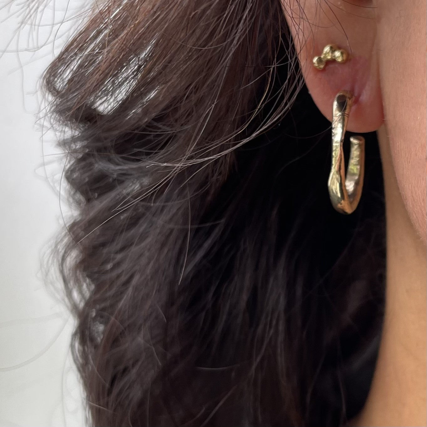 The Satori 18kt Gold Hoop Earrings and 18kt Gold Hoshi Stud Earrings on a person.