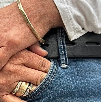 Skipping Stones Simple Bracelet in Bronze with Black Diamonds and ring stack on a person