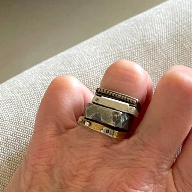 Close-up of a hand wearing Solar Terrain Ring in Silver with Trinity Ring stack