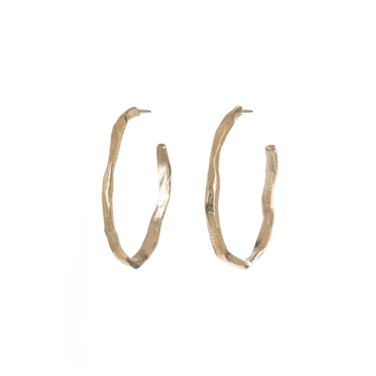 A bold re-imagining of the classic hoop earring. These striking pieces feature a richly textured surface that evokes the weathered, timeless beauty of ancient monoliths. The Stonehenge Hoops are designed to elevate any look, from casual day wear to elegant evening attire. Their substantial presence ensures they make a statement, while the carefully balanced proportions keep them comfortable for all-day wear.