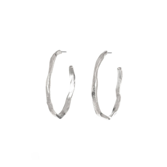 A bold re-imagining of the classic hoop earring. These striking pieces feature a richly textured surface that evokes the weathered, timeless beauty of ancient monoliths. The Stonehenge Hoops are designed to elevate any look, from casual day wear to elegant evening attire. Their substantial presence ensures they make a statement, while the carefully balanced proportions keep them comfortable for all-day wear.