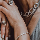 Close-up of hands with jewelry including rings and a bracelet.