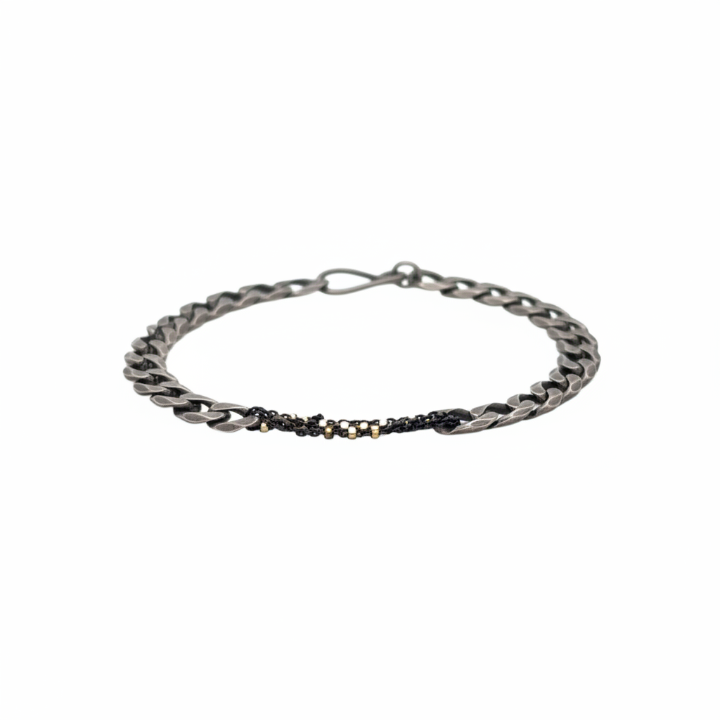 The Binding Light Bracelet pairs a hand-finished oxidized curb chain with a woven center chain of black with gold highlights, symbolizing the way contrast becomes resilience. It evokes the beauty of what’s been mended, tended, or held with intention.&nbsp;
