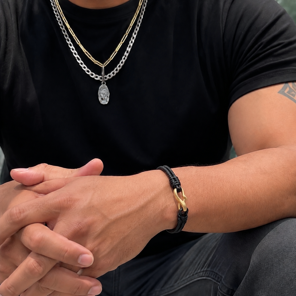Male model wearing gold link chain with hope talisman pendant layered with curb chain. Also wearing the Interwoven Bracelet with Bronze Clasp.
