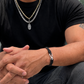 Male model wearing Interwoven Bracelet with silver clasp + curb chain + gold link chain with hope talisman pendant. 