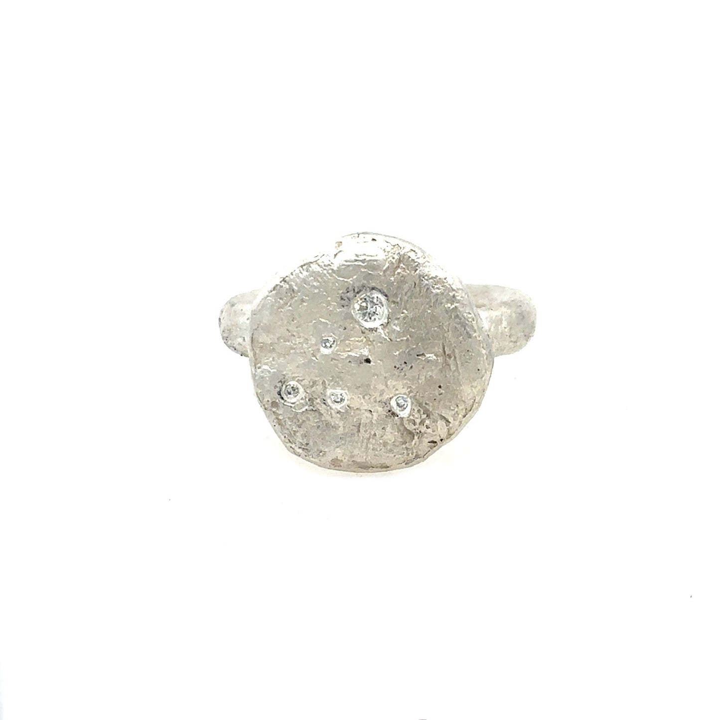 The surface of celestial bodies tells the story of their transformation – impacts and eruptions that forever changed their landscape. This textured disc ring captures that same raw beauty that mimics the terrain of distant worlds and the scattered diamonds appear like stars emerging from cosmic dust.