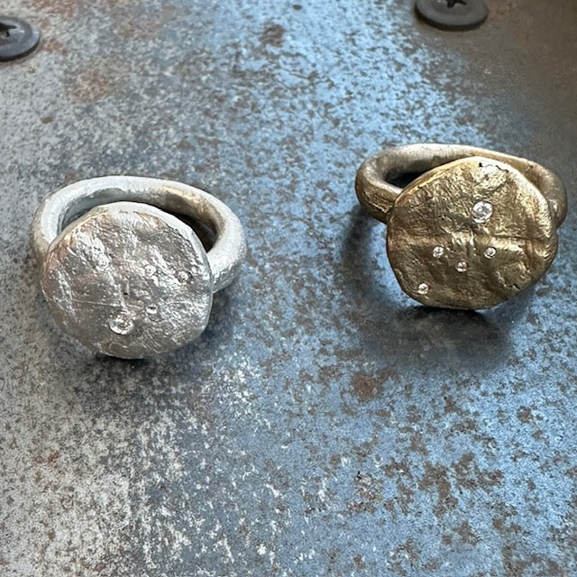 The surface of celestial bodies tells the story of their transformation – impacts and eruptions that forever changed their landscape. This textured disc ring captures that same raw beauty that mimics the terrain of distant worlds and the scattered diamonds appear like stars emerging from cosmic dust.