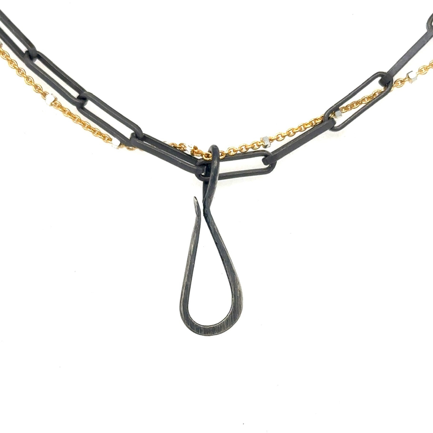 A blend of two worlds in one exquisite piece. This necklace features two chains: one in sophisticated black oxidized sterling silver and the other in luxurious 14K gold-filled metal. The contrasting tones create a subtle yet striking visual interest, perfect for those who appreciate nuanced style. Shown with Tear Drop Connector. 