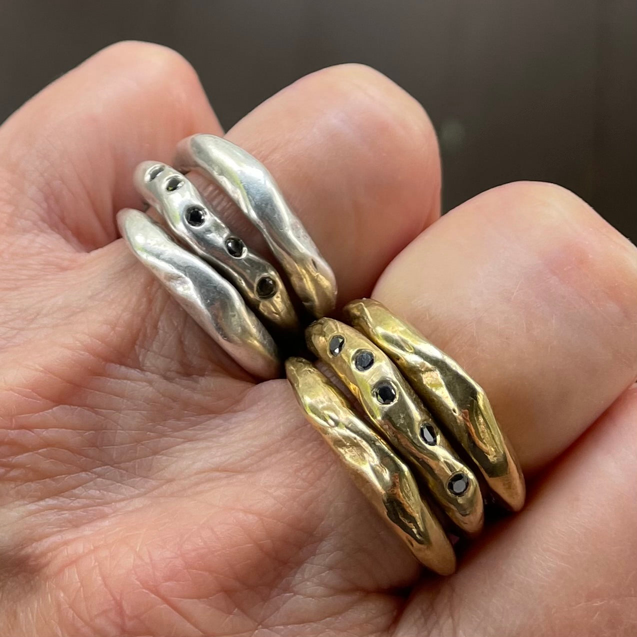 The Connection Stacking Ring Sets shown in Silver and Bronze on persons hand  