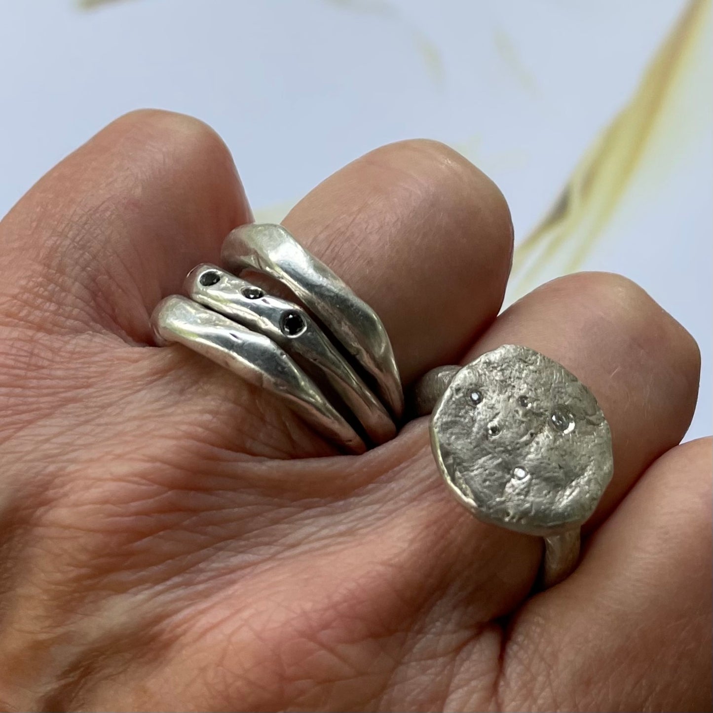 Cosmic Crater Ring in silver with Stack of Element and Constellation Rings in silver on persons hand