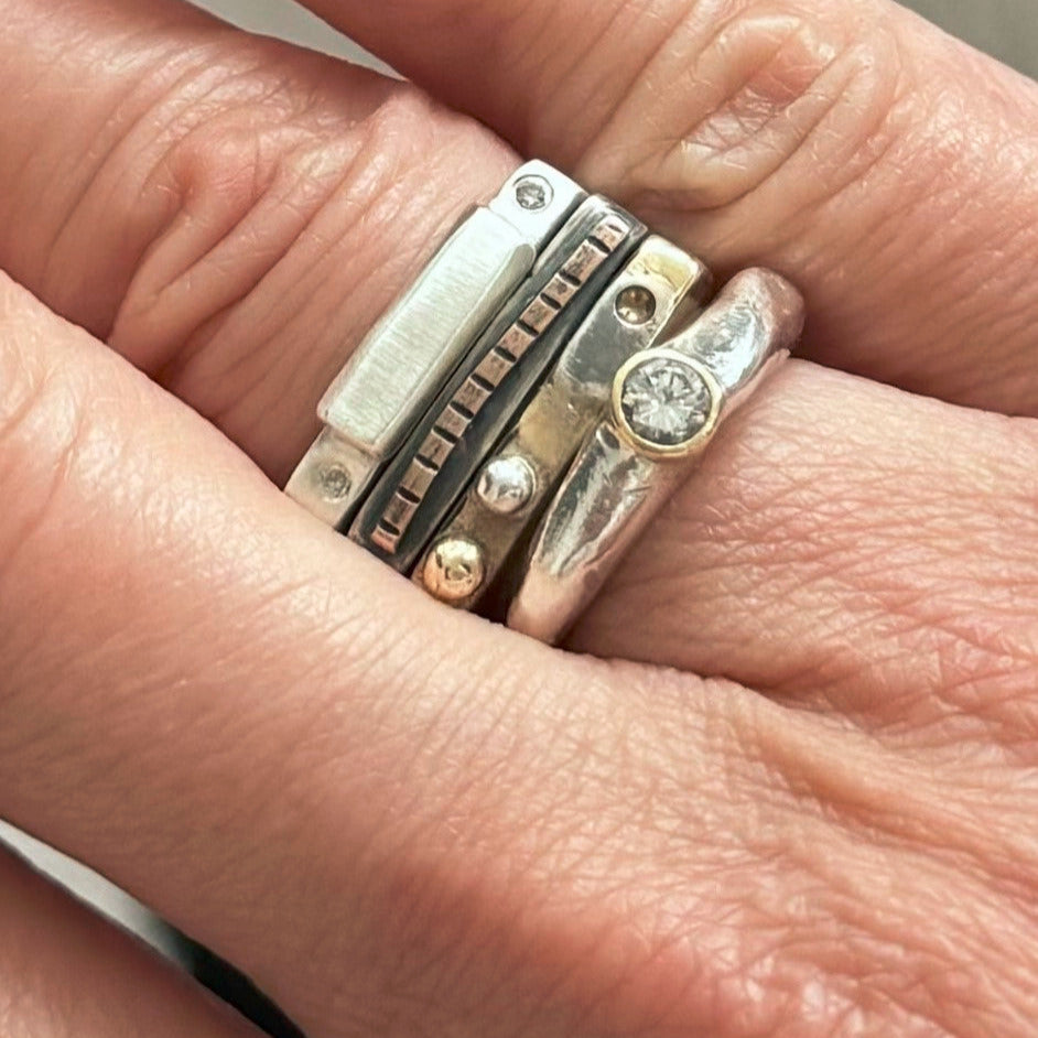 Close-up of a hand wearing Trinity Ring Stack and Devotion Ring in Silver with White Diamond