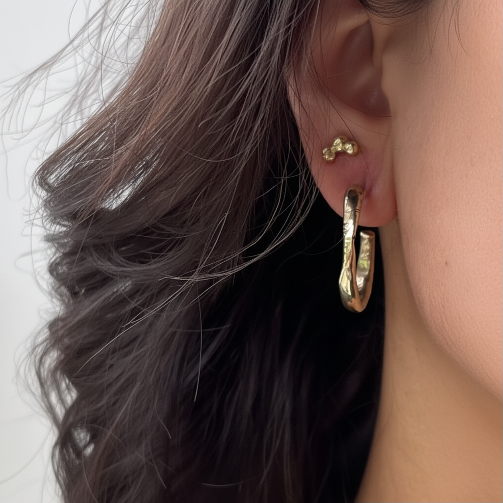The Satori 18kt Gold Hoop Earrings and 18kt Gold Hoshi Stud Earrings on a person. 