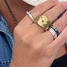 Hand wearing Five Elements Ring in Bronze; Odyssey Ring in Silver; Deep Mystic Ring with Diamonds and personal stack of silver rings