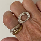 Close up of Ovum Ring in Silver with Diamond and Bronze and Silver Odyssey Rings on hand 