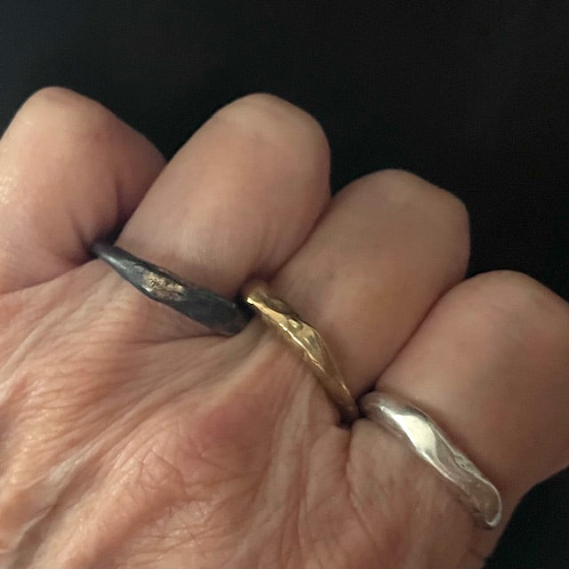 Close-up of a hand wearing Oxidized Silver with Gold Accents; Bronze; Silver Element Rings 