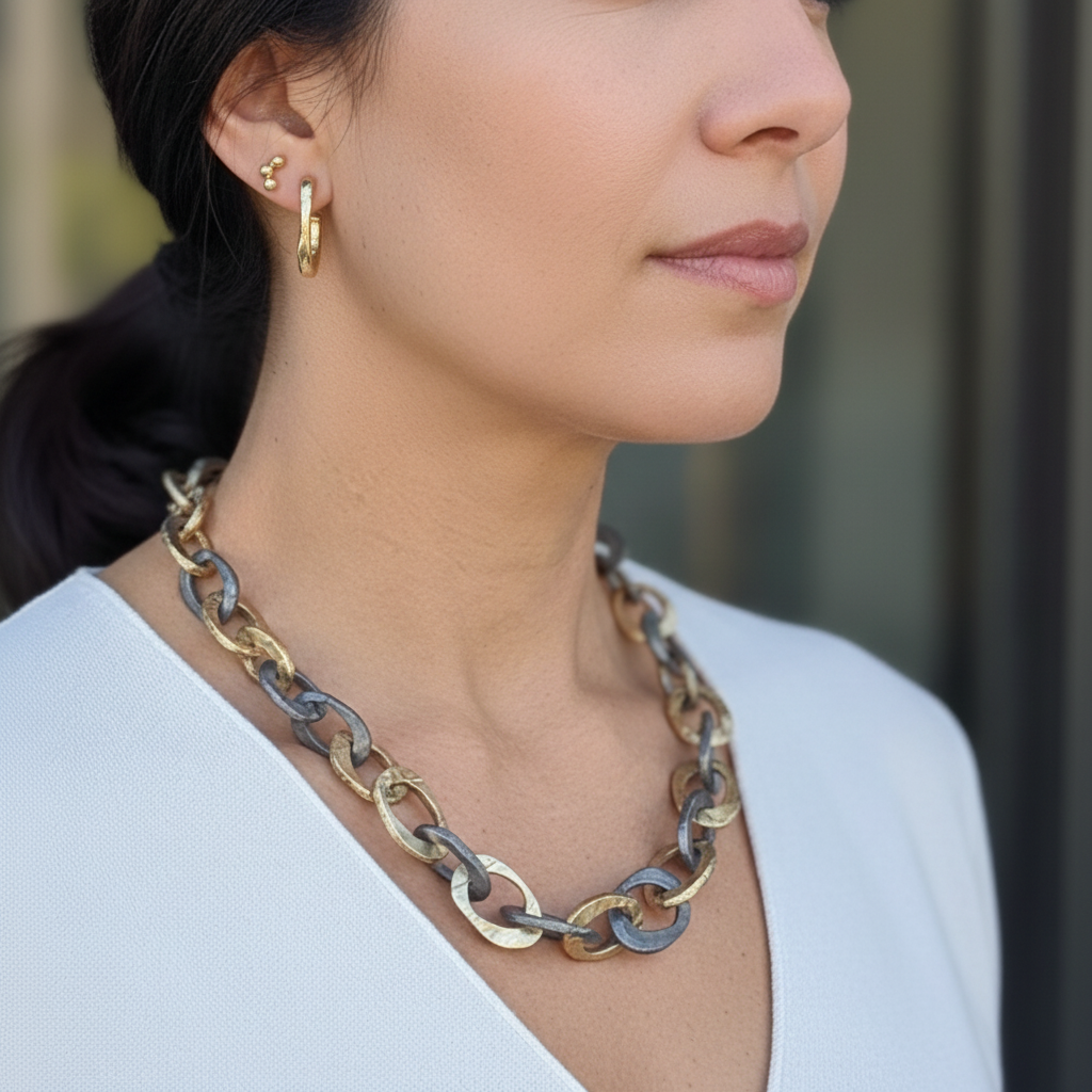 The Illumina Link Necklace is a bold mixed-metal necklace in bronze and oxidized silver. Hand-sculpted links celebrate strength, connection, and wabi-sabi beauty. Shown with the Satori Hoop and Hoshi Stud Earrings.