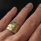 Close-up of a hand wearing the Origin Ring in Bronze against a black background