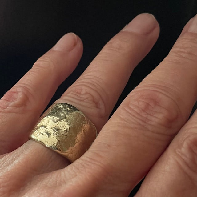 Close-up of a hand wearing the Origin Ring in Bronze against a black background