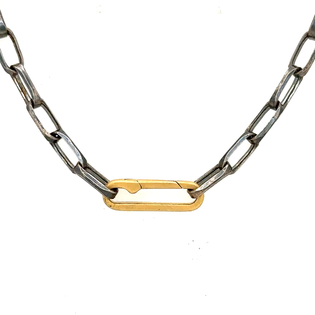An oxidized silver chain necklace with a gold paper clip connector serving as the clasp, positioned against a white background.