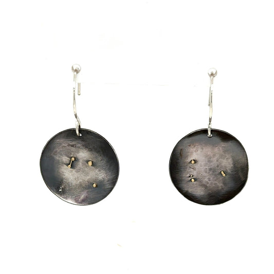 Adorn yourself with a piece of Whidbey Island's ever-changing sky with our Sunbreak Earrings. These stunning oxidized silver discs capture the elusive dance of clouds and sunlight that paints the island's heavens in an ever-shifting tableau.

Each earring is a canvas of deep, oxidized silver, reminiscent of the moody gray clouds that often blanket Whidbey's skies and it's the perfect backdrop for the touches of gleaming gold that adorn the surface. 