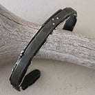 This sterling silver cuff features a subtly curved form that hugs the wrist, mimicking the arc of waves of Whidbey Island as they curl towards the shore. The surface of the cuff is a canvas of textures and features 3 white diamonds, both evoke different aspects of Whidbey's dynamic coastal environment.