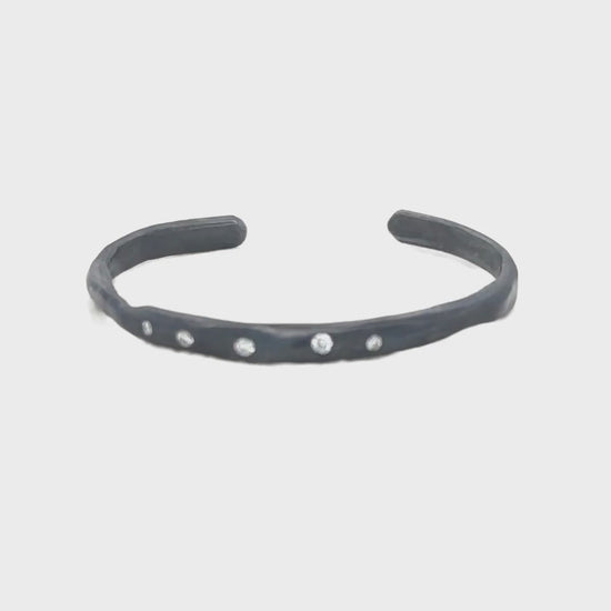 The Divine Light Cuff is a slender oxidized silver cuff illuminated with white diamonds. A symbol of serenity and luminous strength.