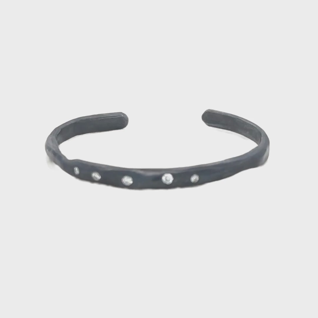 The Divine Light Cuff is a slender oxidized silver cuff illuminated with white diamonds. A symbol of serenity and luminous strength.