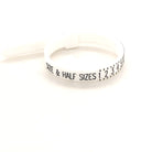 A ring sizer tool with markings for measuring ring sizes, placed on a plain background.