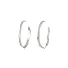 A bold re-imagining of the classic hoop earring. These striking pieces feature a richly textured surface that evokes the weathered, timeless beauty of ancient monoliths. The Stonehenge Hoops are designed to elevate any look, from casual day wear to elegant evening attire. Their substantial presence ensures they make a statement, while the carefully balanced proportions keep them comfortable for all-day wear.